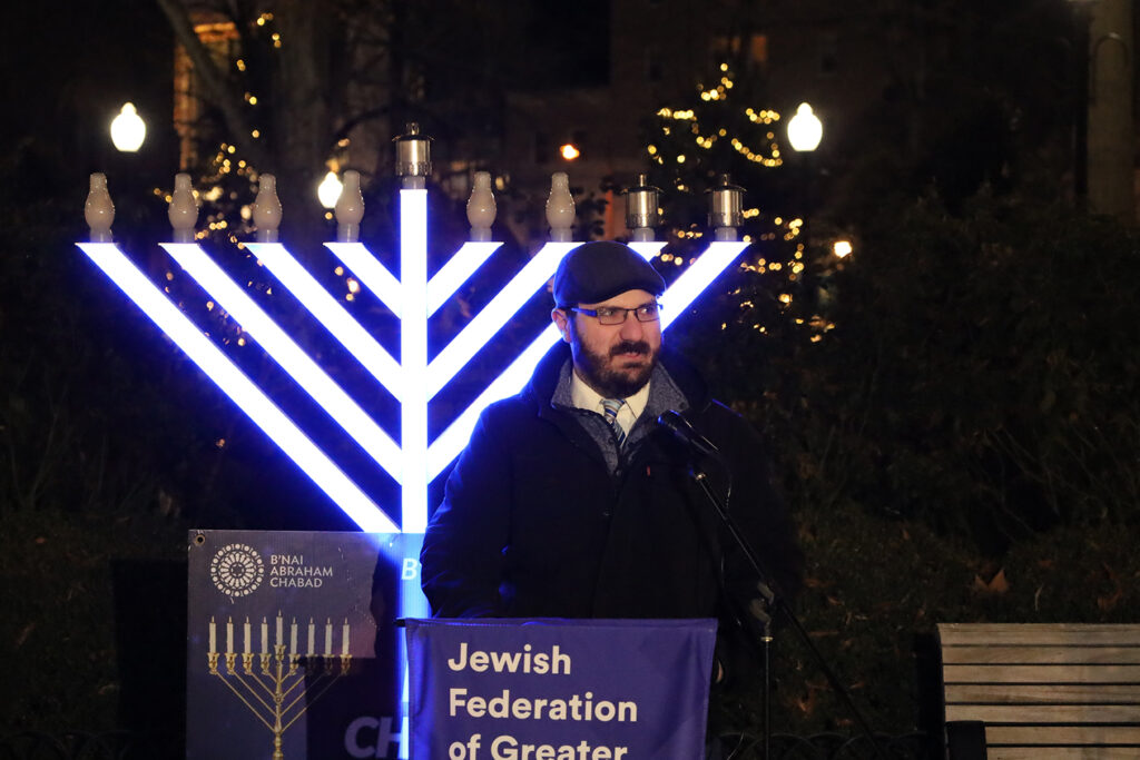 A male rabbi speaks in front of a menorah in Philadelphia