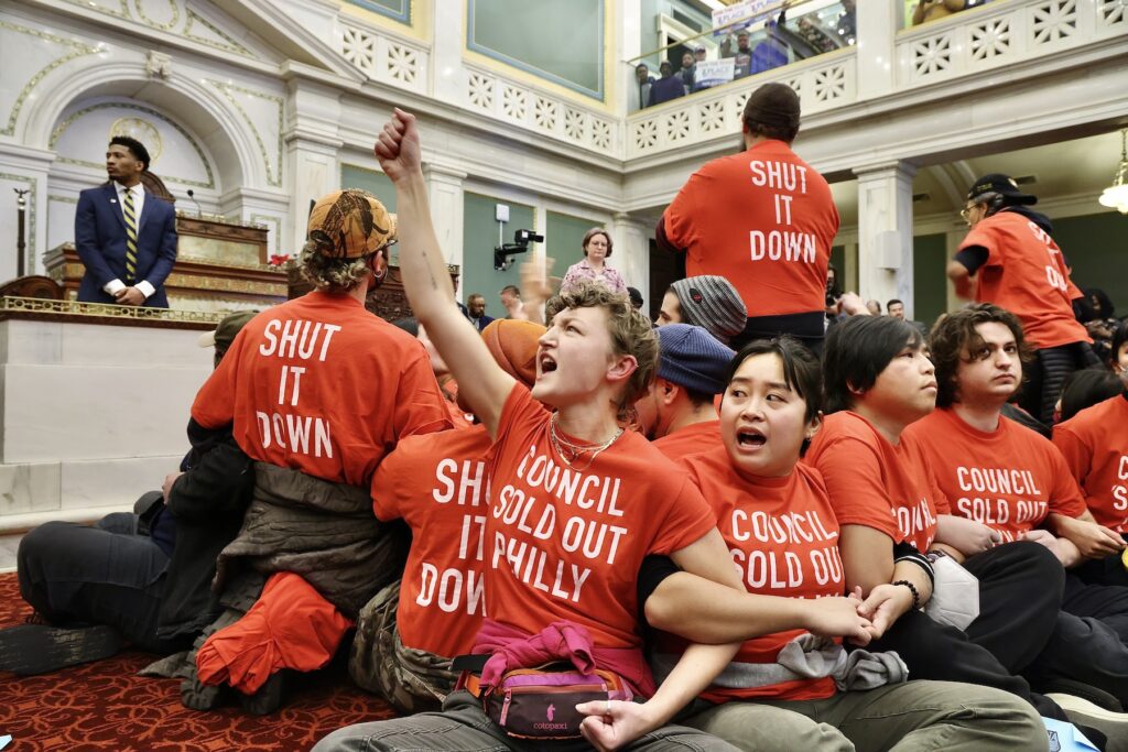sixers-arena-council-protest-e-lee-2024-12-19-6 Protesters sitting on the floor and locking arms
