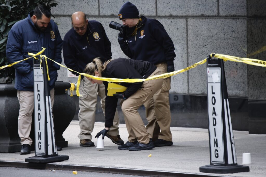 APTOPIX UnitedHealthcare CEO Killed Members of the New York police crime scene unit pick up cups marking the spots where bullets lie as they investigate the scene outside the Hilton Hotel in midtown Manhattan where Brian Thompson, the CEO of UnitedHealthcare, was fatally shot Wednesday, Dec. 4, 2024, in New York.
