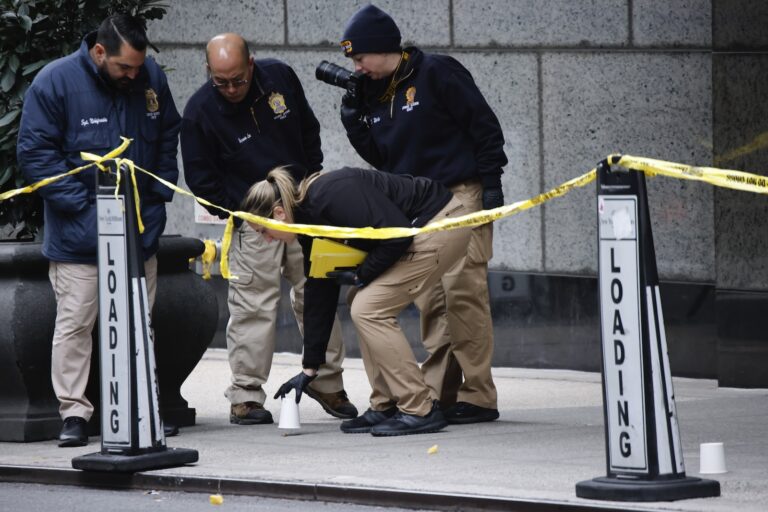 Members of the New York police crime scene unit pick up cups marking the spots where bullets lie as they investigate the scene outside the Hilton Hotel in midtown Manhattan where Brian Thompson, the CEO of UnitedHealthcare, was fatally shot Wednesday, Dec. 4, 2024, in New York.