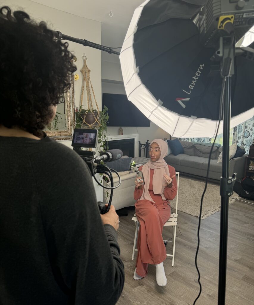 Wilson-Anton sitting in a chair with big lighting equipment facing her