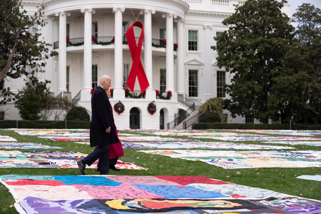 world-aids-day-2024-white-house-quilt-biden Joe and Jill Biden walk between AIDS Memorial Quilts spread over the South Lawn at the White House