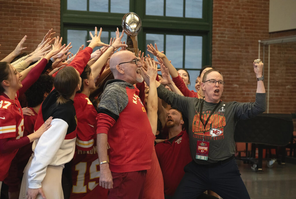 kc_chiefs_ballet_01312025 Kansas City Ballet Artistic Director Devon Carney leads a cheer holding the Lombardi trophy with a group of people reaching for it