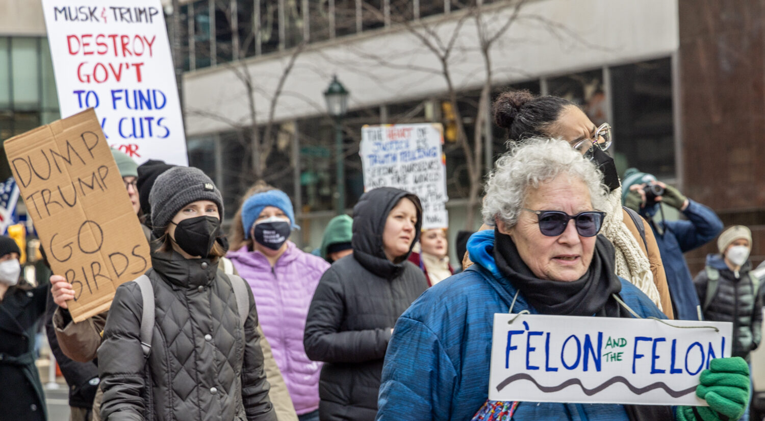 people carrying signs, one reading FELON AND THE FELON and another reading DUMP TRUMP GO BIRDS