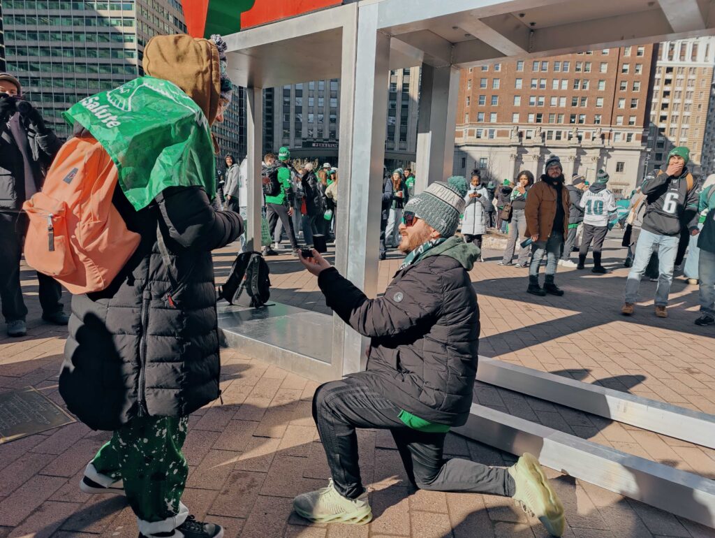 02142025_eagles_parade_love3 Nicholas Maestrale got down on one knee to pop the question to Olivia Dees during the Eagles victory parade. (Peter Crimmins/WHYY)