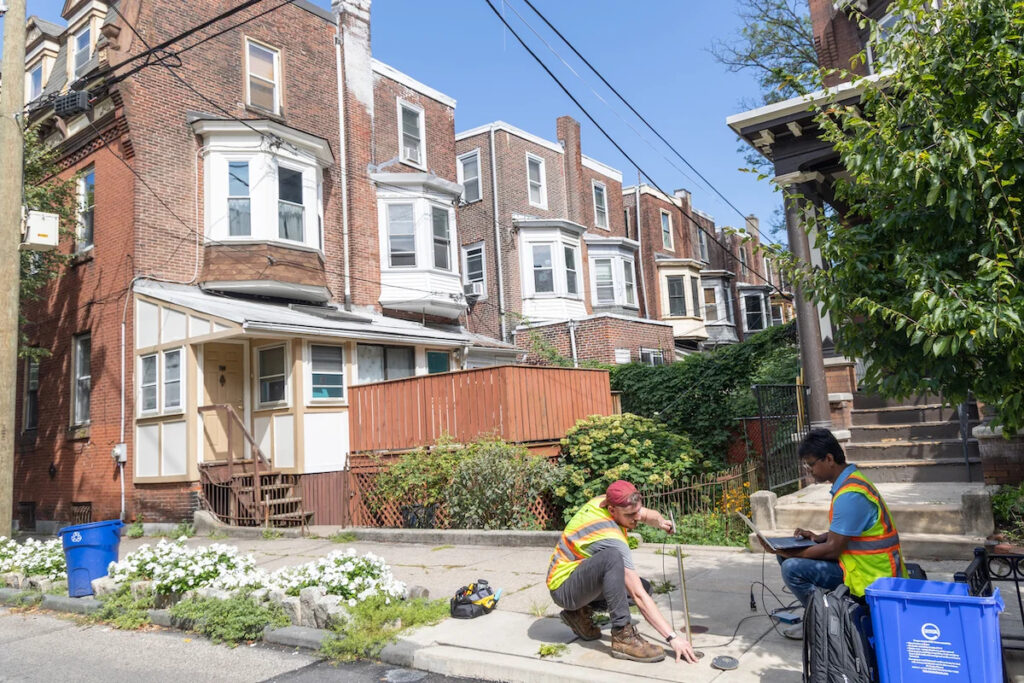 08-17-2023-k-paynter-everett-skipper-vp-cornwell-PWD-pilot-detect-lead-pipes-6-file two researchers hammering into the ground outside rowhouses