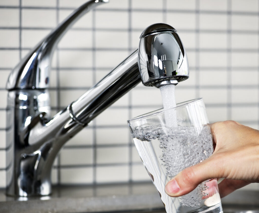 Filling Glass Of Tap Water Filling glass of water from stainless steel kitchen faucet. (Bigstock/elanathewise)