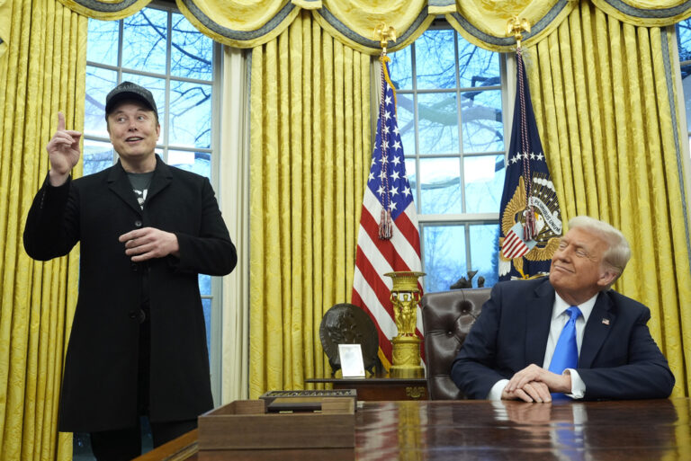 Donald Trump listens as Elon Musk speaks