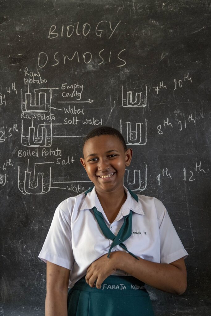 A student poses for a photo in front of a chalkboard