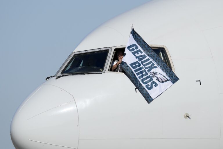 A pilot waves a flag out of the cockpit window that says 'Geaux Birds'