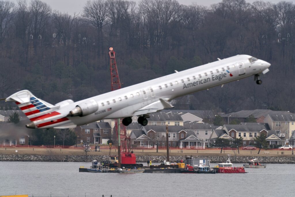 Plane Crash Crews recover wreckage from the crash as another plane takes off overhead