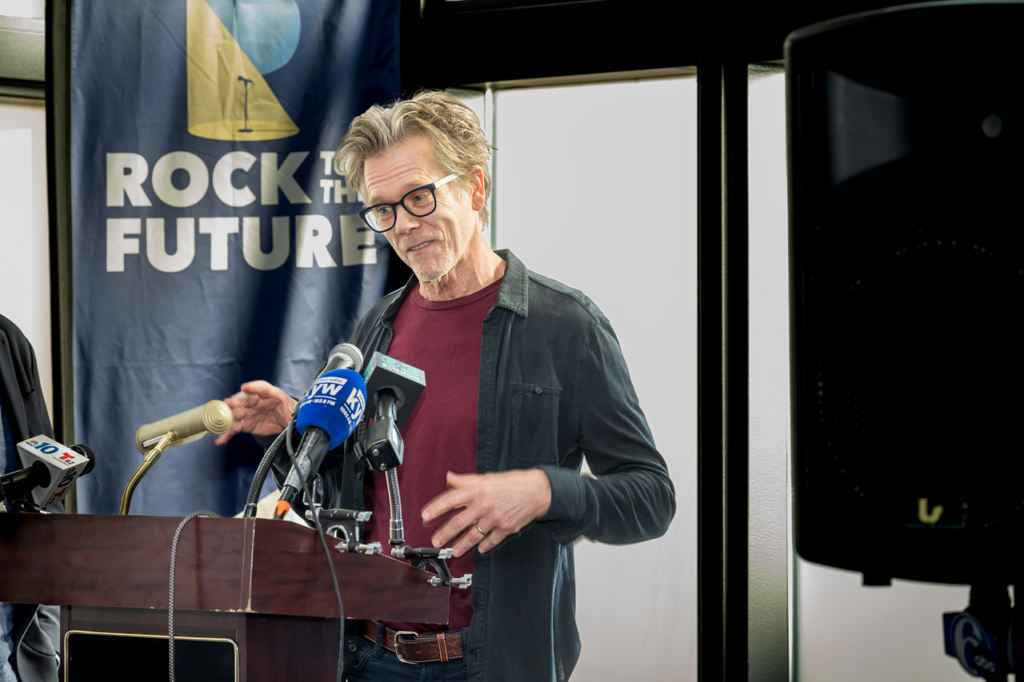 kevin-bacon-2025 Kevin Bacon speaks at a podium