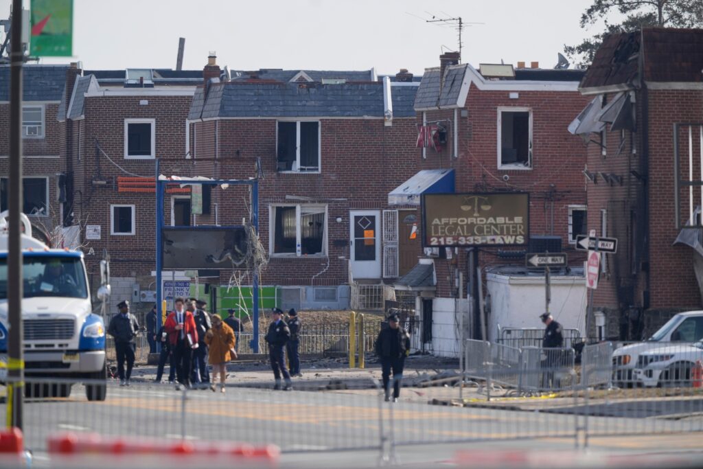 philadelphia-plane-crash-2025-02-03 police officers outside damaged structures in the aftermath of a fatal small plane crashed in Philadelphia