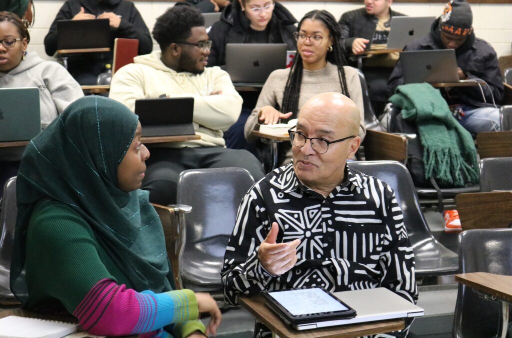 rutgers_senior_03012025 A man in a college classes talks with a female student to his right