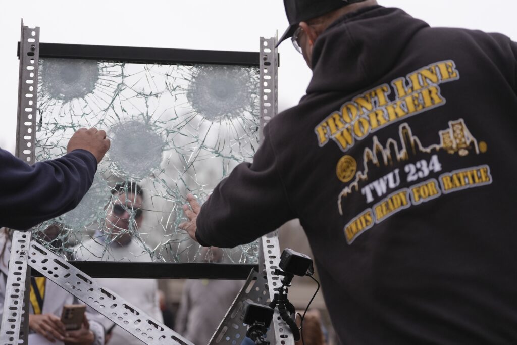 A man taking photos of bulletproof glass after it had been shot