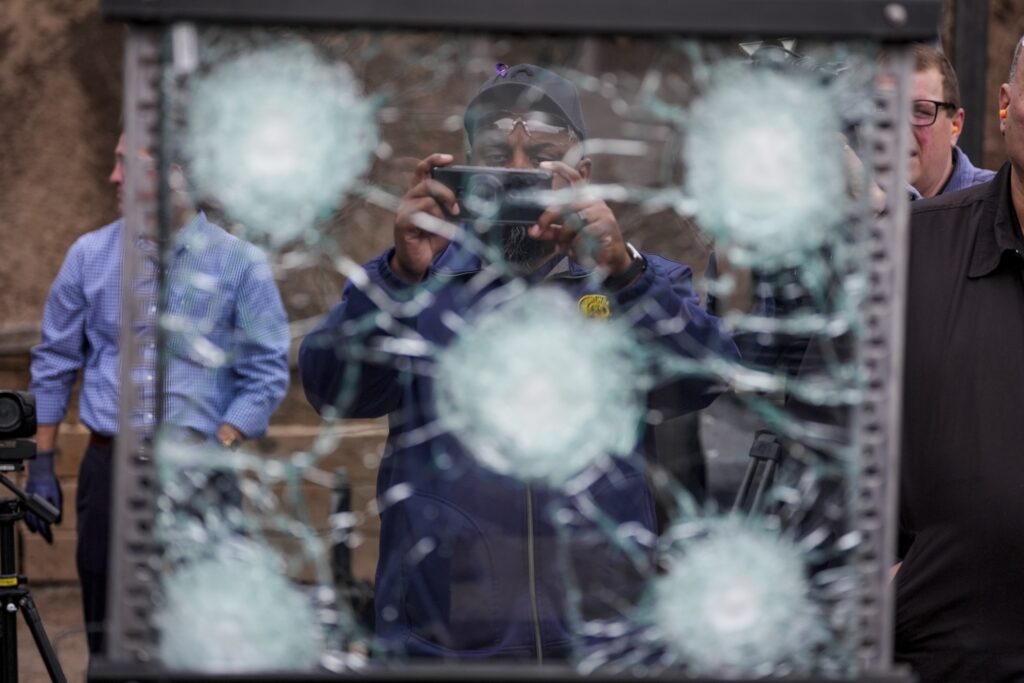 A man taking photos of bulletproof glass after it had been shot