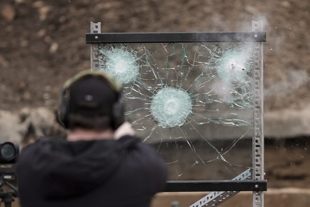 Bus Driver Safety A man shooting a gun at a piece of bulletproof glass as a test