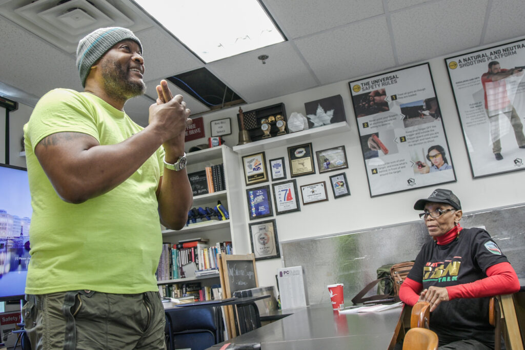 A man gestures to his class, teaching them gun safety
