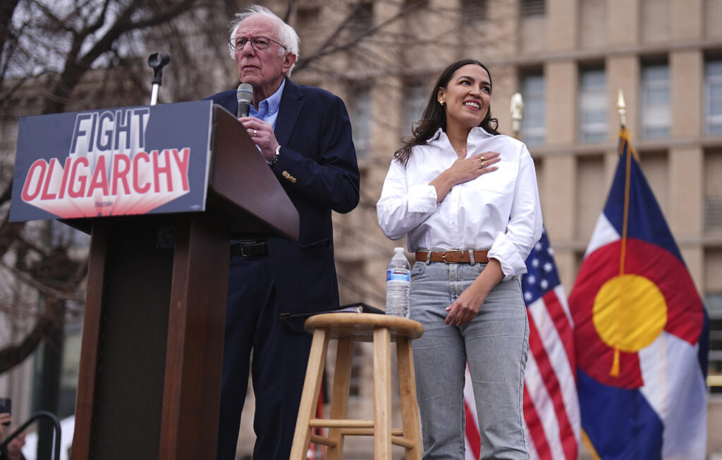 AOC, Bernie Sanders Sen. Bernie Sanders, I-Vt., left, speaks as Rep. Alexandria Ocasio-Cortez, D-N.Y., responds to calls of support during a stop of their