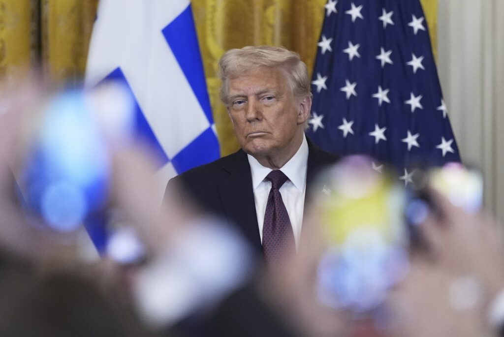 Trump Donald Trump sitting in front of American and Greek flags