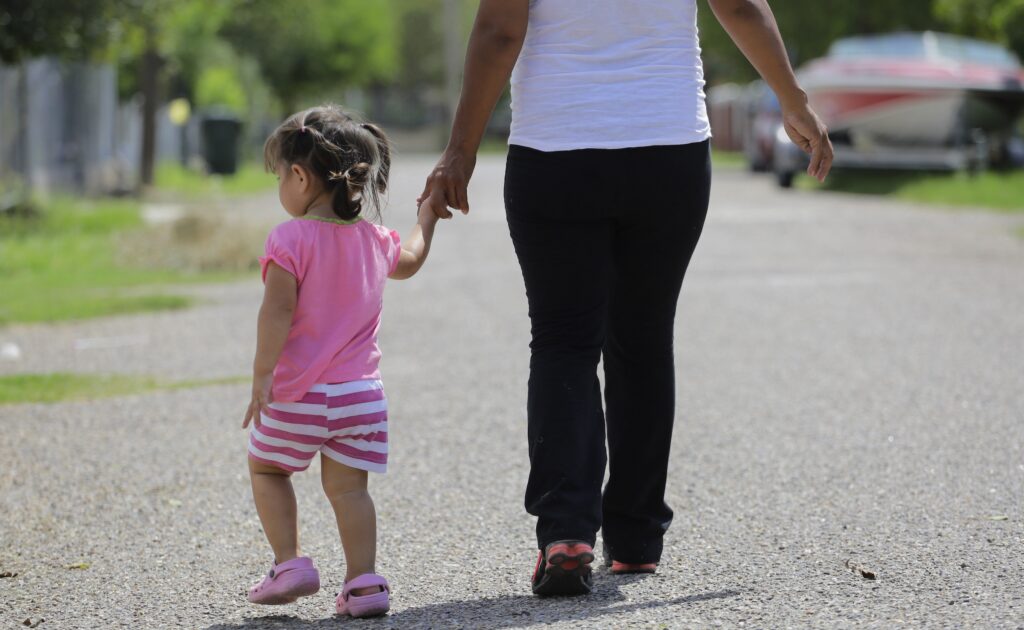 Birthright Citizenship Explainer A young girl walking down the street holding onto a woman's hand