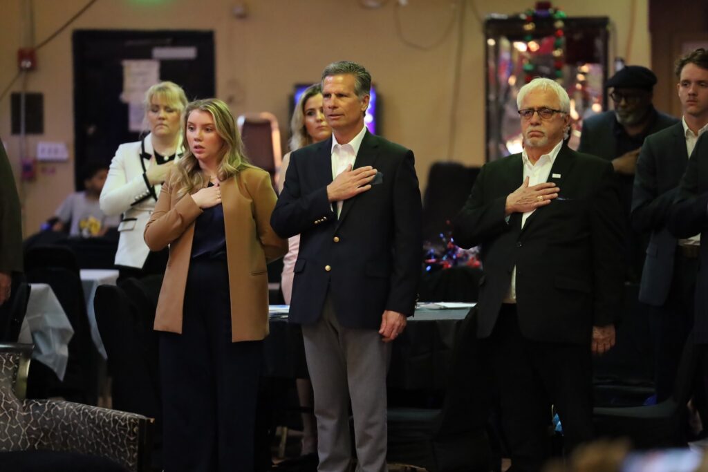 Dan Meuser and other with their hands over their heart for the pledge of allegience