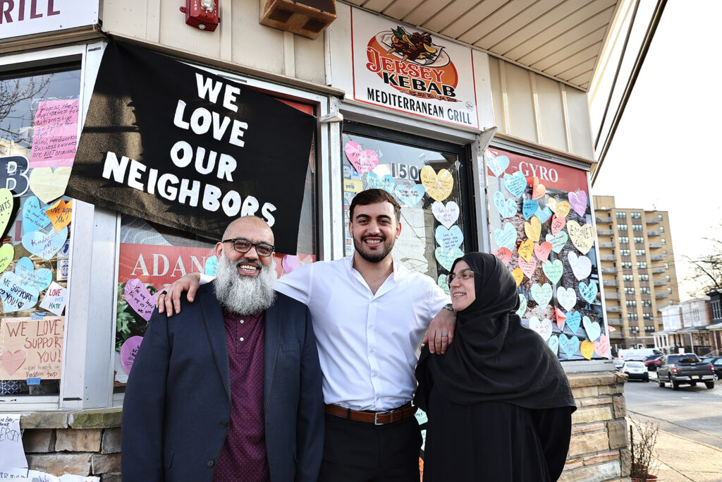 The owners of a New Jersey restaurant who were detained by immigration officers and their son embrace each other outside of the restaurant
