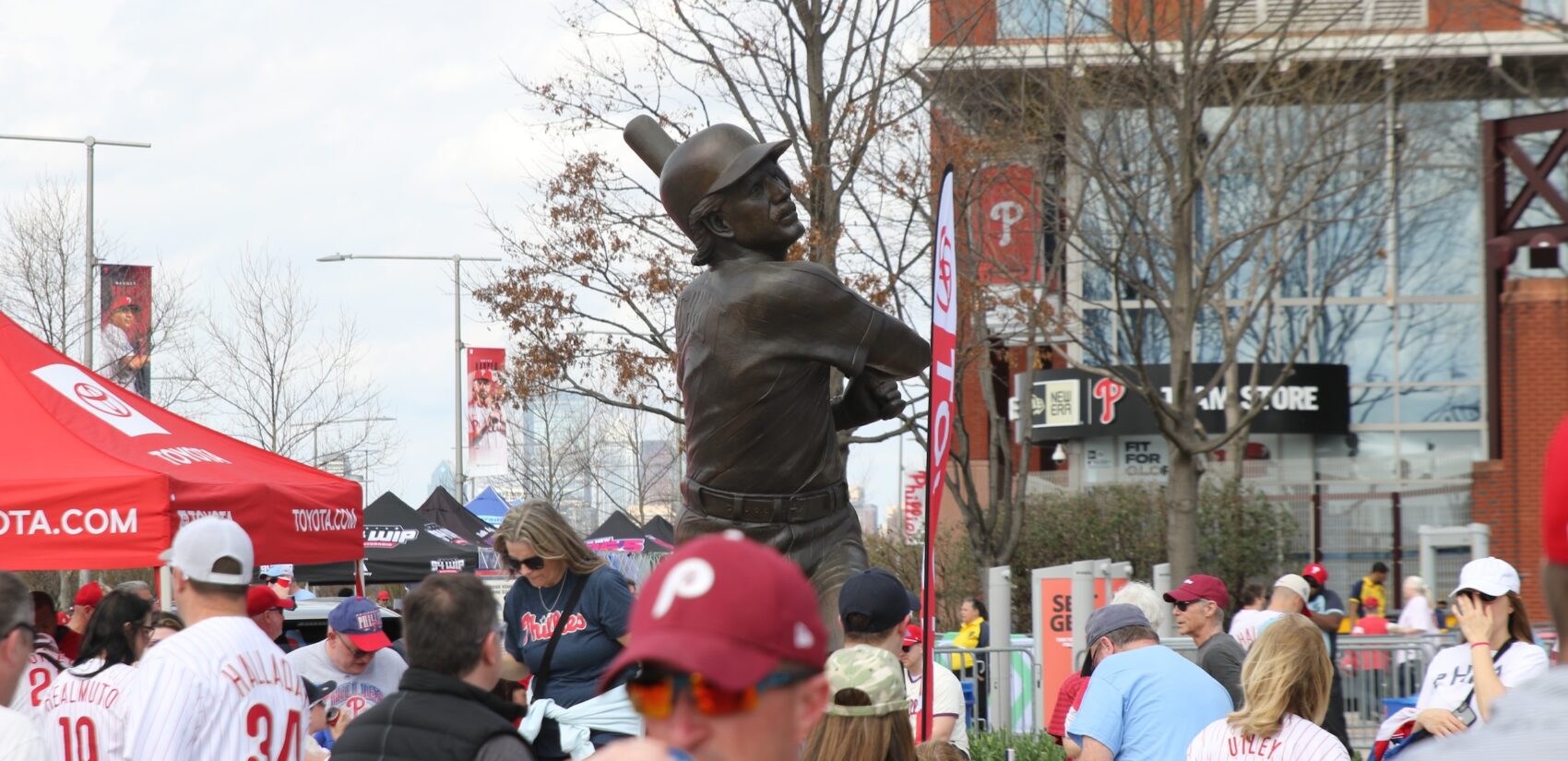 Fans make their way into the stadium, walking past a statue of Mike Schmidt