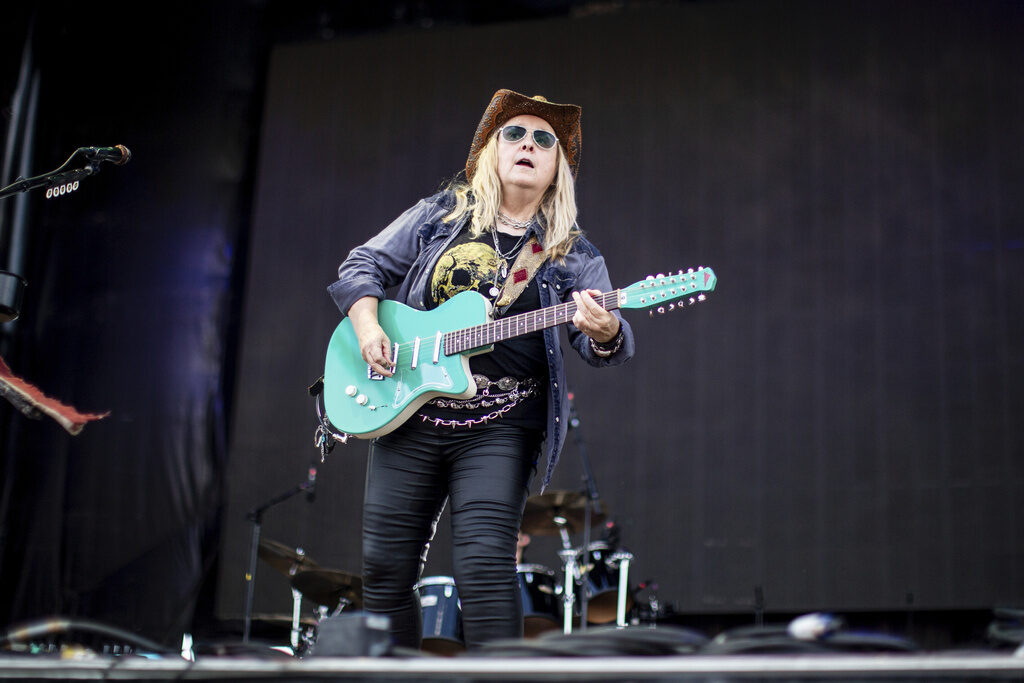 Musician Melissa Etheridge plays a blue electric guitar on stage