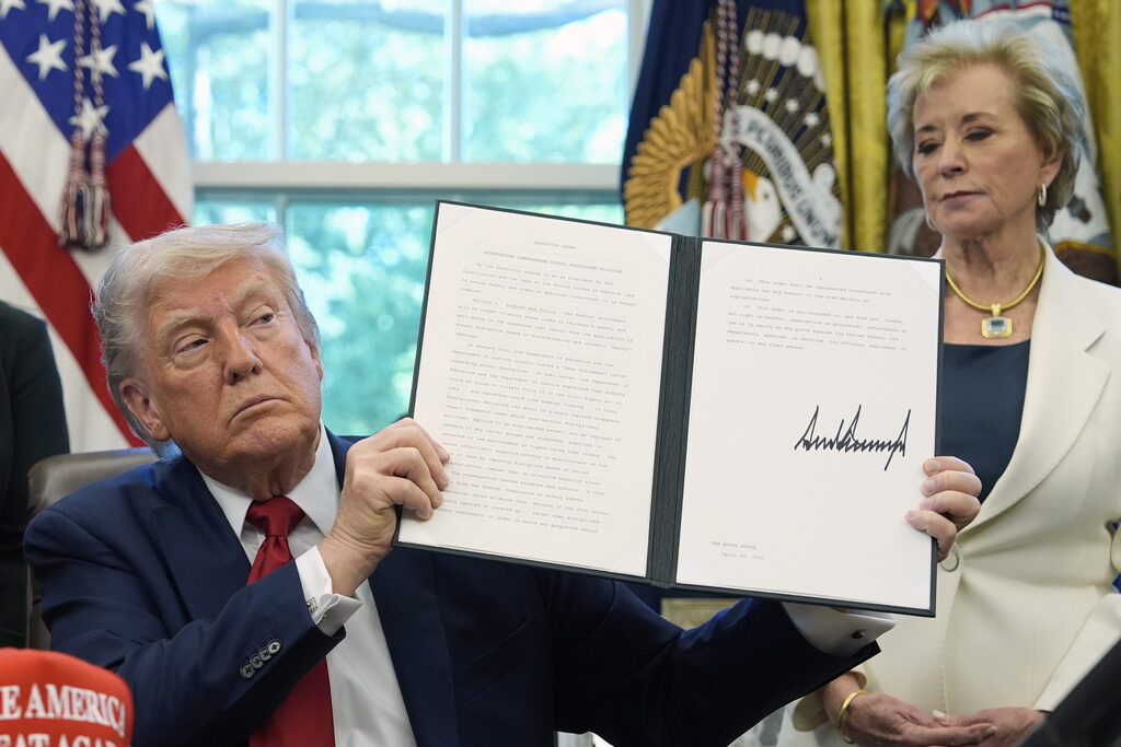 Trump President Donald Trump holds up a signed executive order with education secretary Linda McMahon behind him