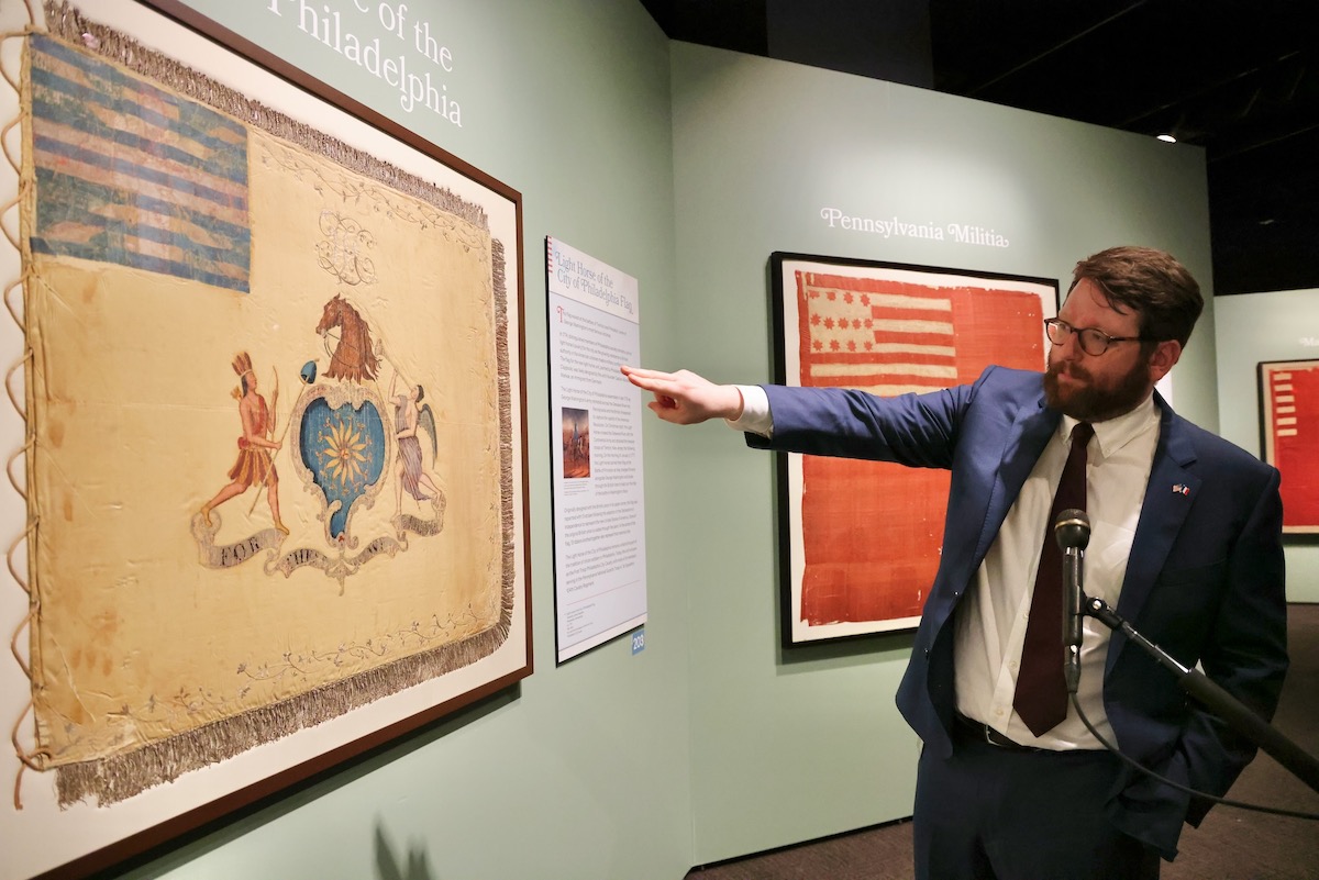 James Taub, associate curator at the Museum of the American Revolution, points at flag on display in the museum