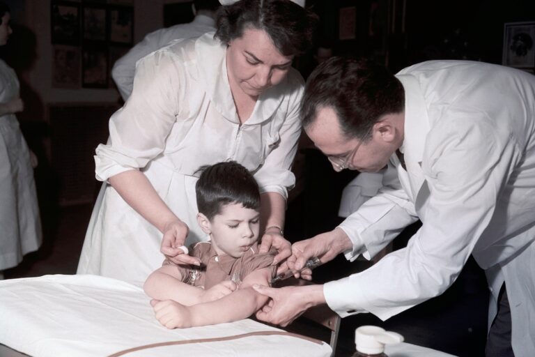 Jonas Salk gives a child a vaccine