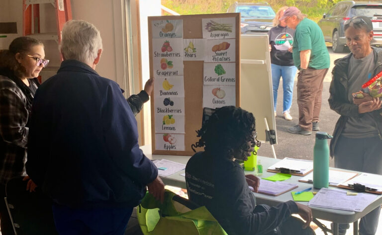 a list of foods offered at a table as residents stand in line