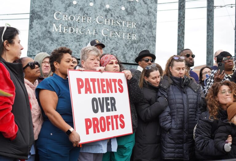Crozer Health staff protesting with a sign reading PATIENTS OVER PROFITS