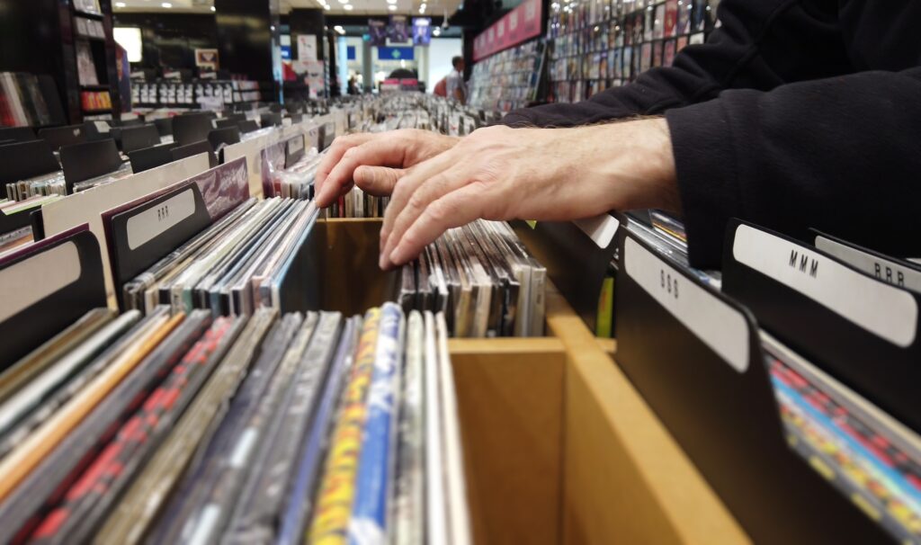 Browsing vinyl in a record store. Close up of hands flipping through lps in a large record shop.