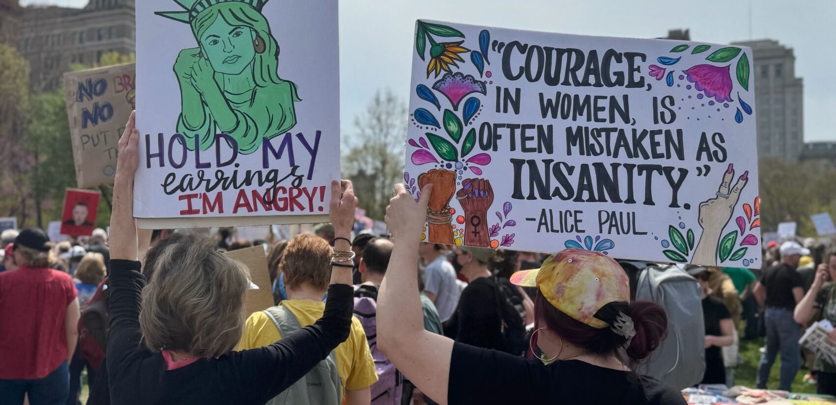 People hold signs protesting the Trump administration at a rally in Philadelphia