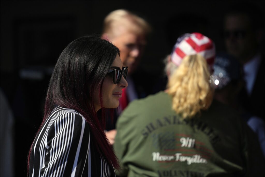 Laura Loomer walking past Donald Trump