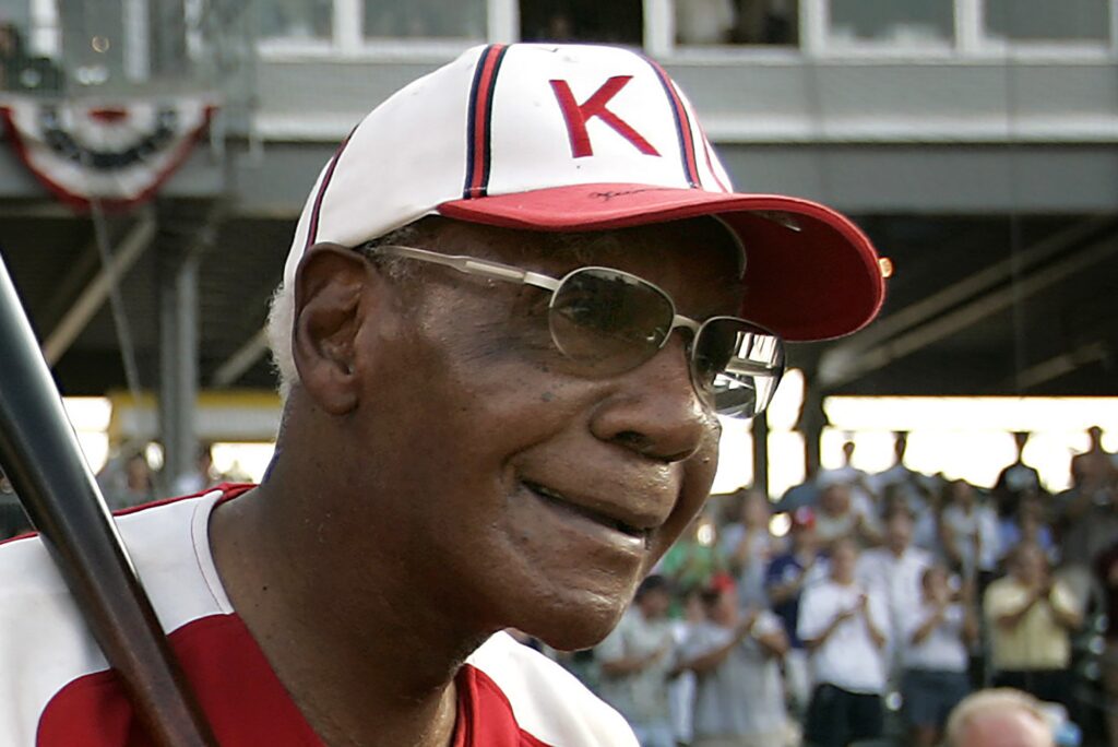 Buck O'Neil posing for a photo with a bat, wearing his old Negro Leagues uniform