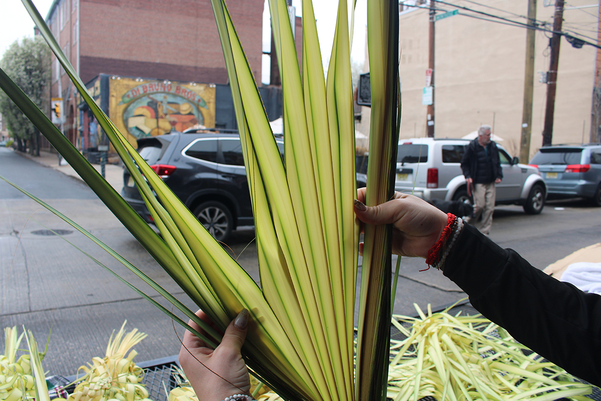 A woman holds palm fronds in Philadelphia's Italian Market.