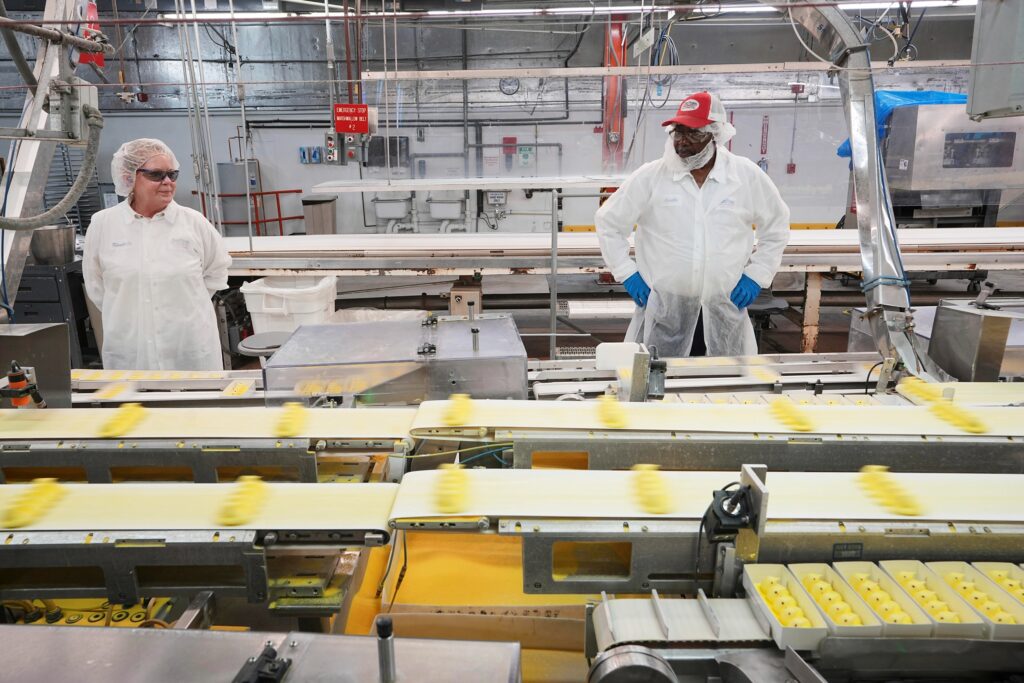 two workers look at the manufacturing line