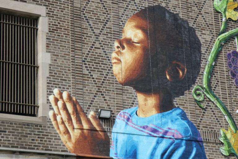 Mural of praying boy on the facade of Saint Malachy School
