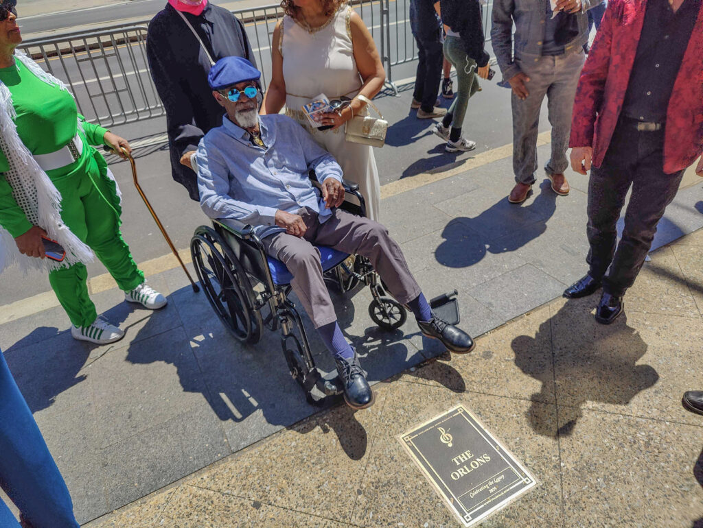 Steven Caldwell sitting in a wheelchair and posing for a photo near the plaque on the Walk of Fame