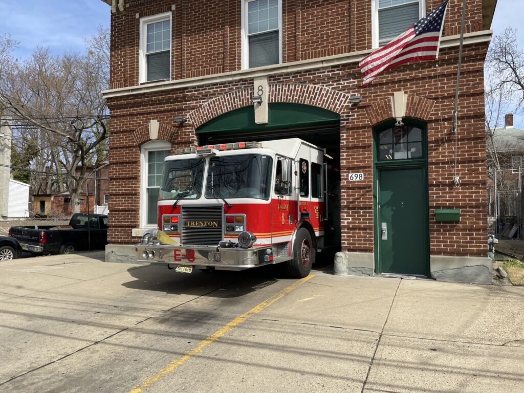 A fire truck sitting in the driveway of the fire house