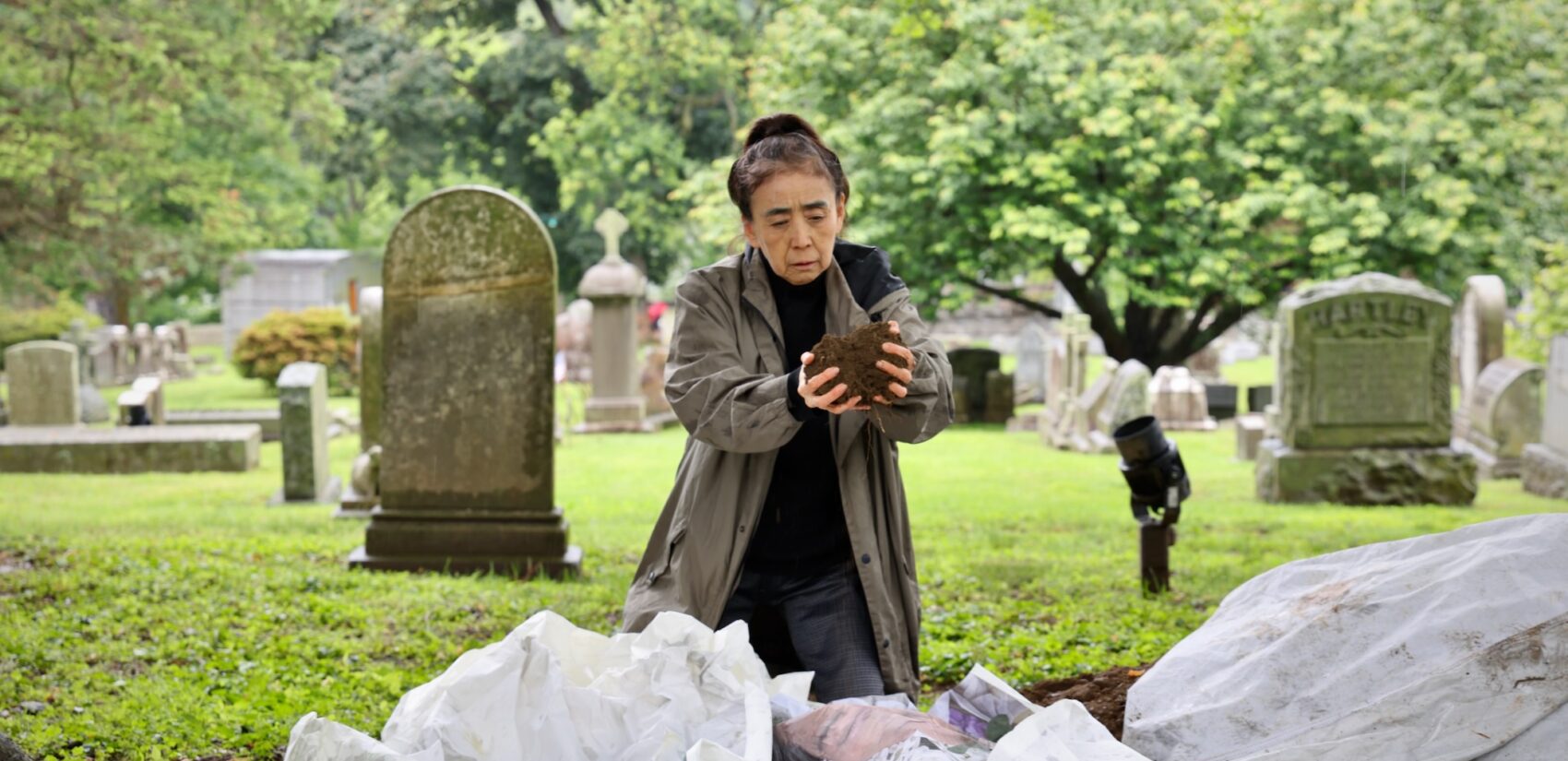 Eiko Otake scatters dirt over an image of her mother at Laurel Hill Cemetery for the Death and Arts Festival