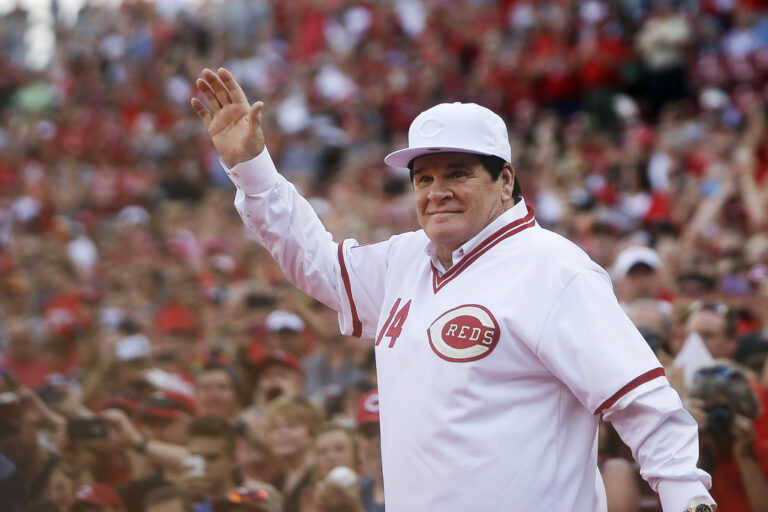 Pete Rose waiving to a crowd while wearing a Cincinnati Reds shirt
