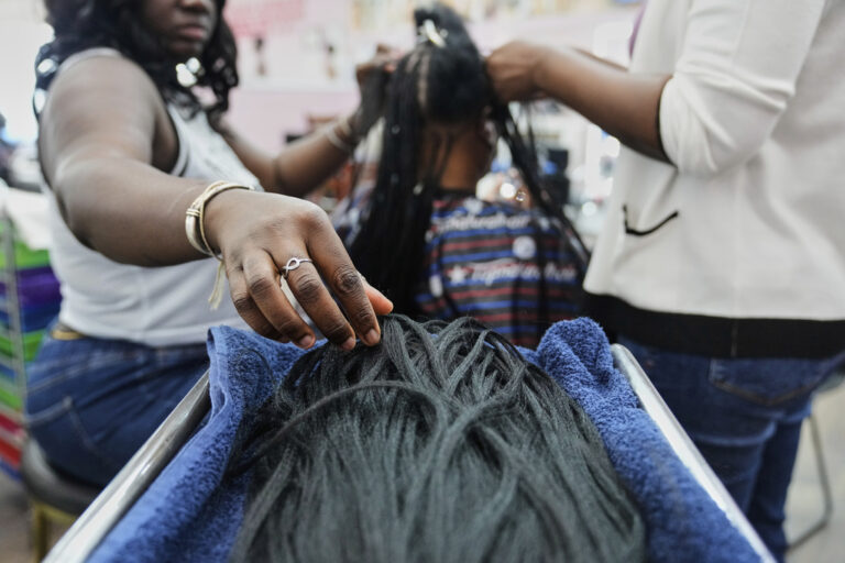 A braider picks up pieces of synthetic braiding hair