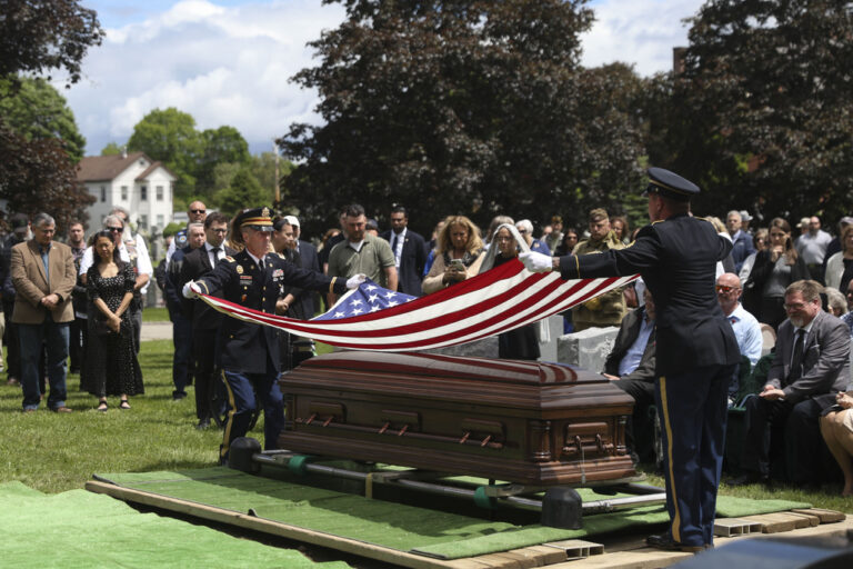 An American flag is folded during the interment for World War II U.S. Army Air Forces Staff Sgt. Eugene Darrigan at the cemetery behind St. Mary's church