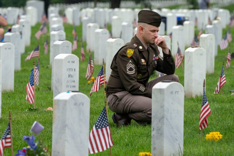 A member of the Army keels by a tombstone in Section 60 of Arlington National Cemetery