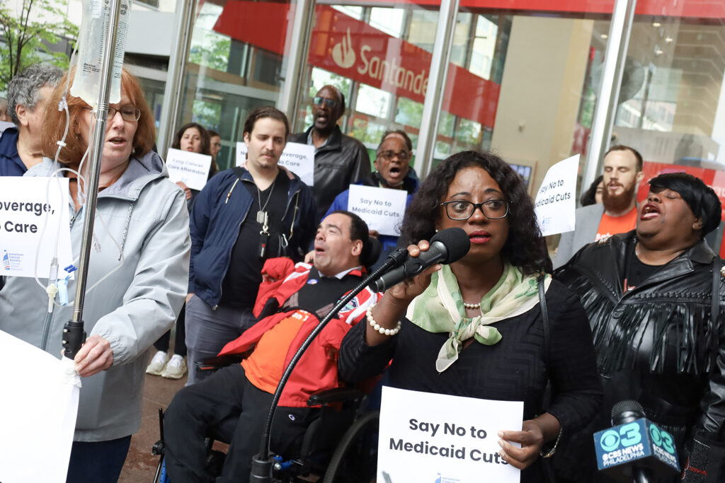 A woman speaks into a microphone at a rally against Medicaid cuts in Philadelphia
