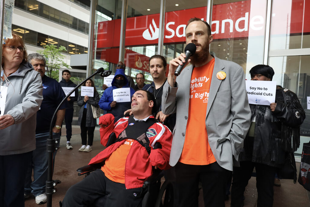 A man speaks into a microphone at a rally against Medicaid cuts in Philadelphia
